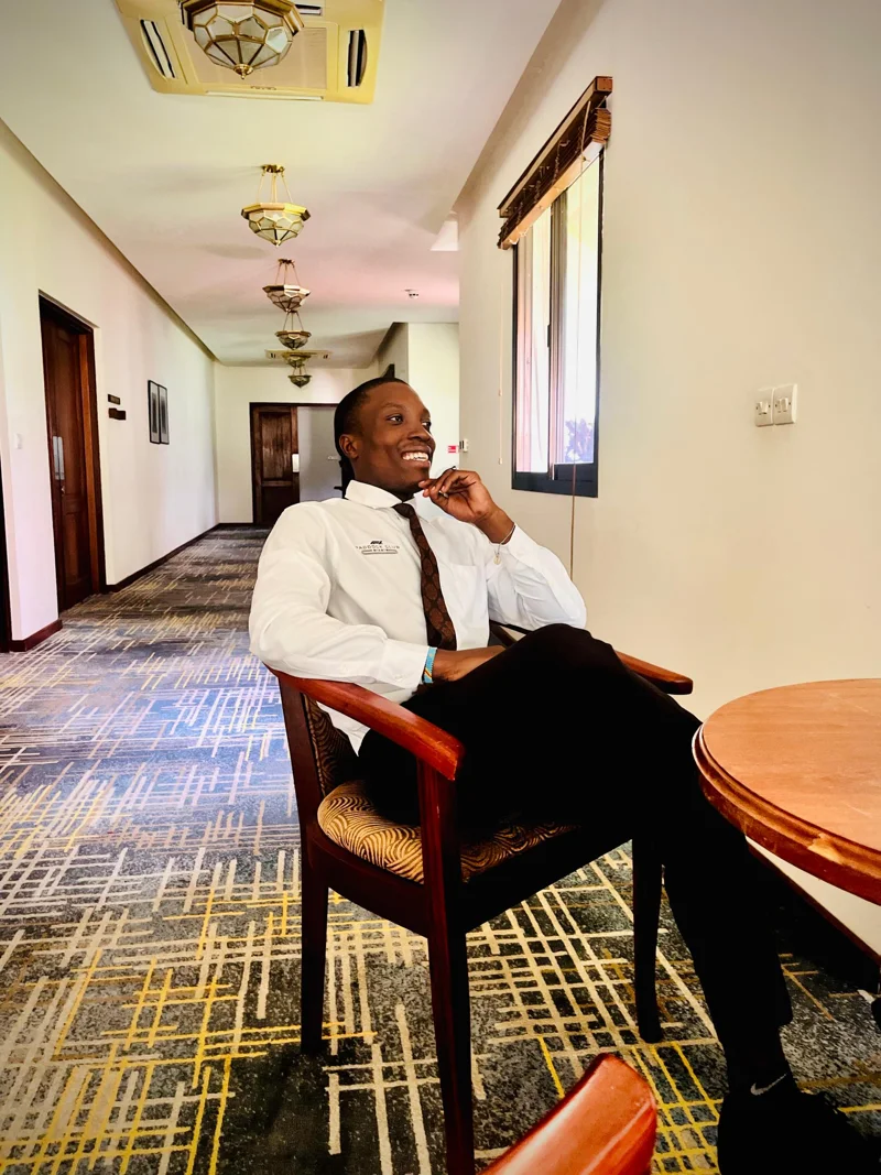 Mickdad Masola smiling, seated in a sunlit hotel lounge